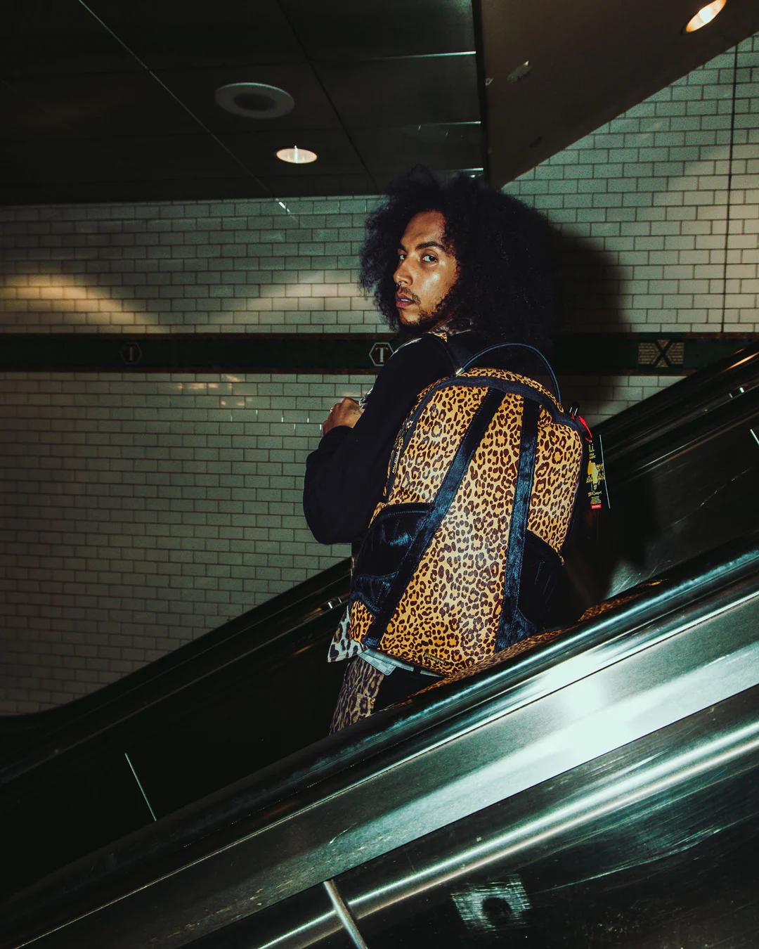 Sprayground Essential | AFRICAN INTELLIGENCE 9 COURAGE LIVES ON BACKPACK - SANDFLOWER COLLAB